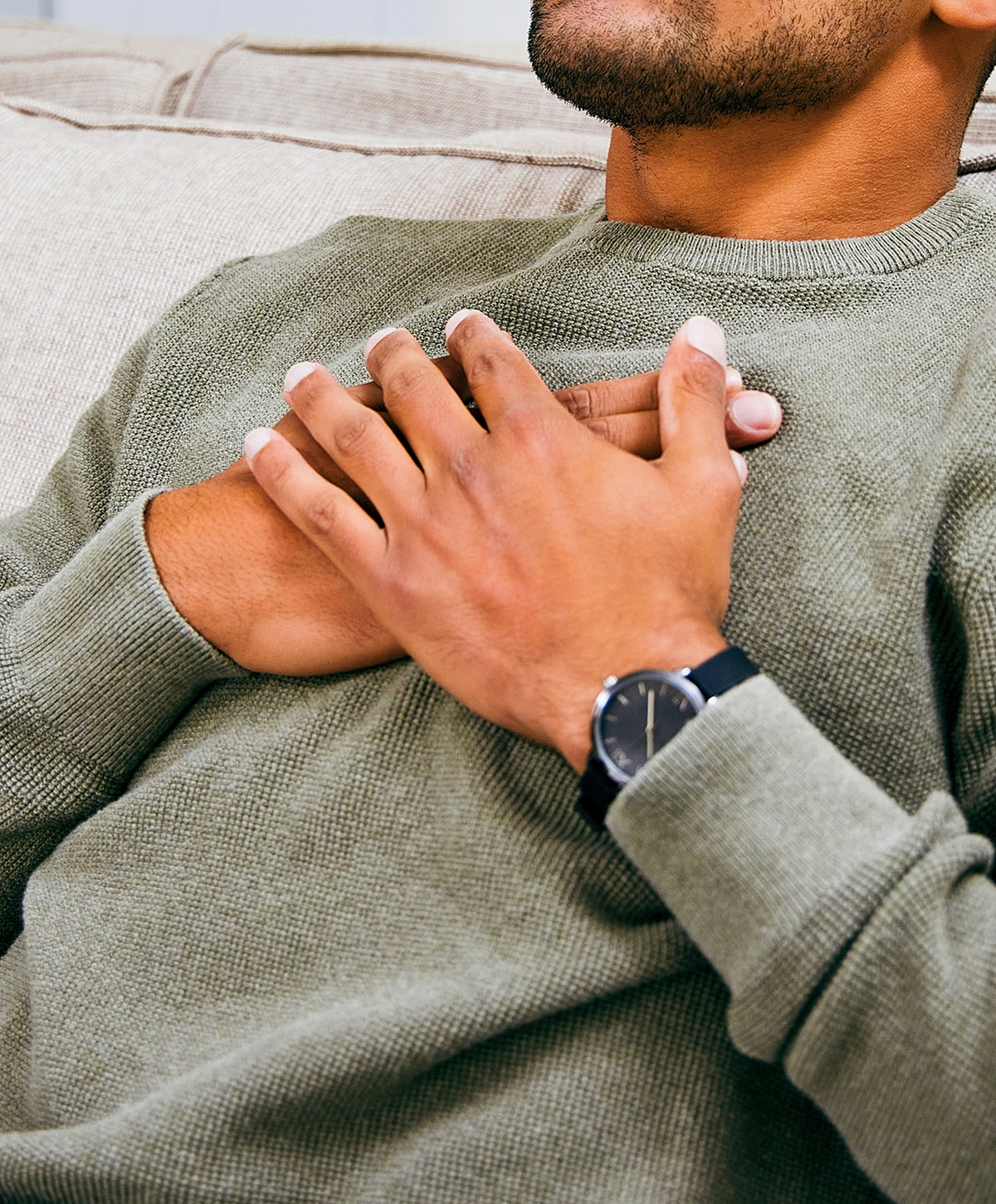 Person sitting with hands clasped on chest.