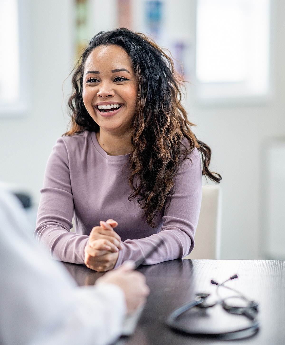 Smiling woman in conversation with healthcare professional.