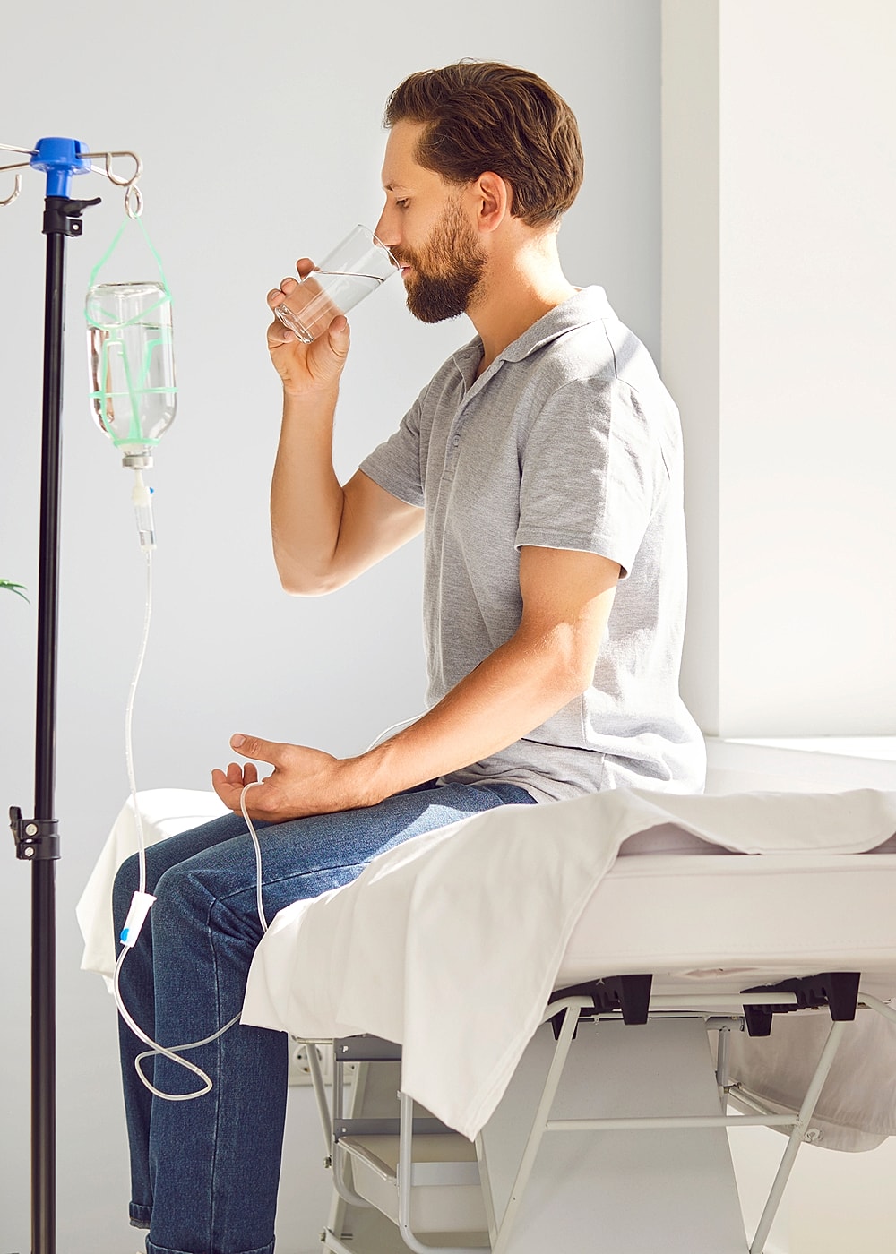 Man drinking water beside IV drip.