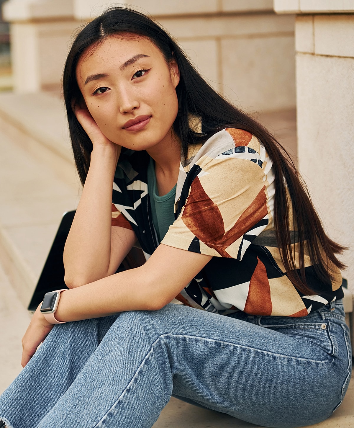 Woman sitting casually with geometric patterned shirt.