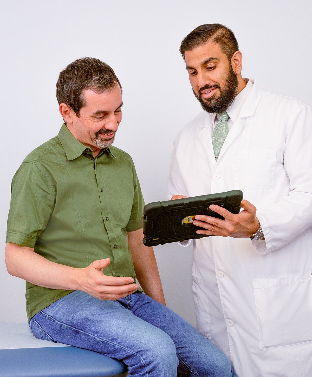 Doctor discussing information with patient on tablet.