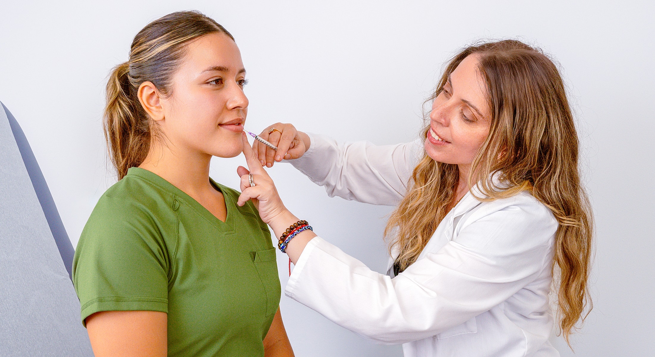 Doctor performing cosmetic procedure on patient’s lips.