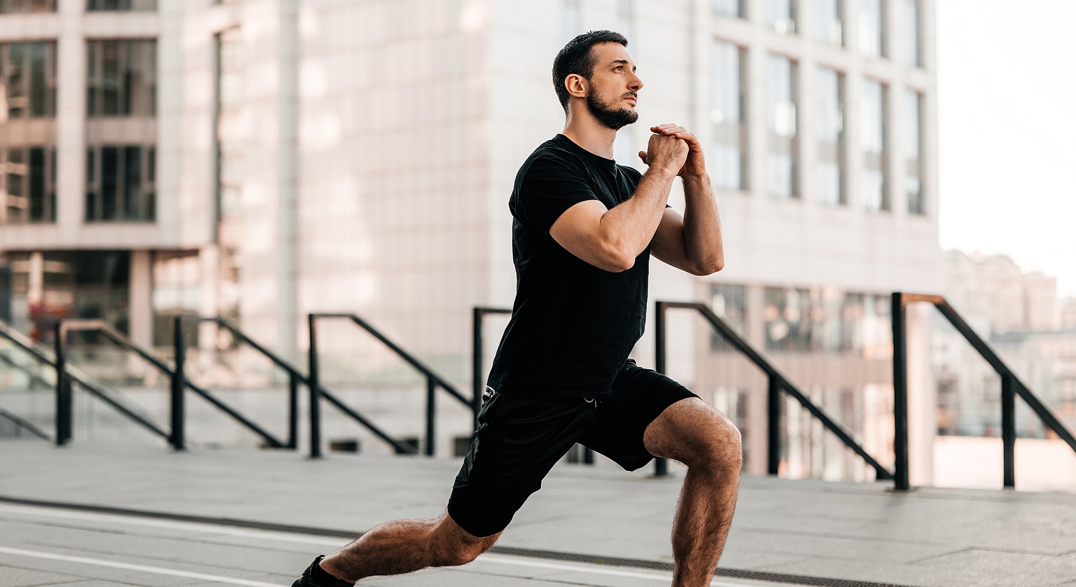 Man performing lunges outdoors in urban setting.